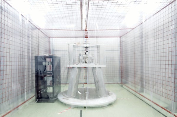 Industrial equipment behind a plastic sheet shown in florescent lighting at medium distance.